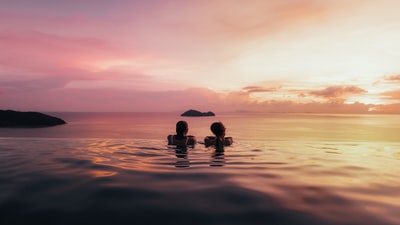 日落时水面上两个人的剪影